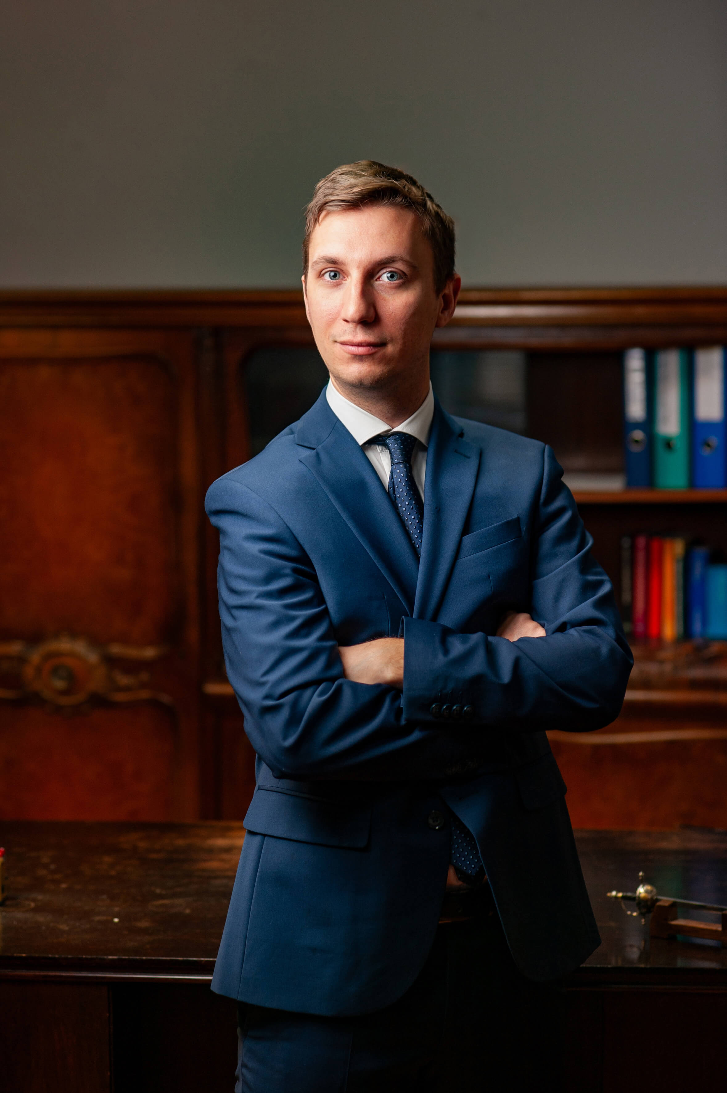 Attorney in a blue suit with arms crossed, standing in a law office